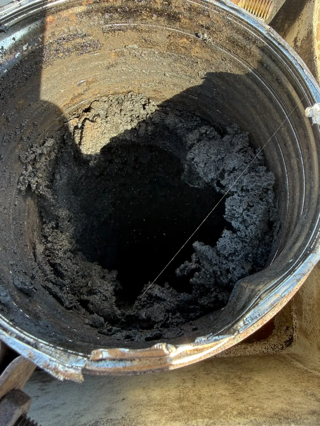 Conduit de cheminée vu du dessus, recouvert d'une épaisse croûte de bistre noir qui réduit la section