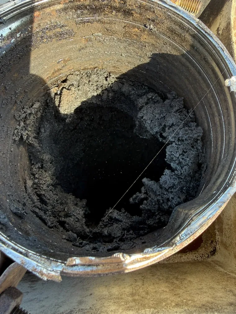 Conduit de cheminée vu du débouché, recouvert d'une épaisse croûte de bistre noir qui réduit la section
