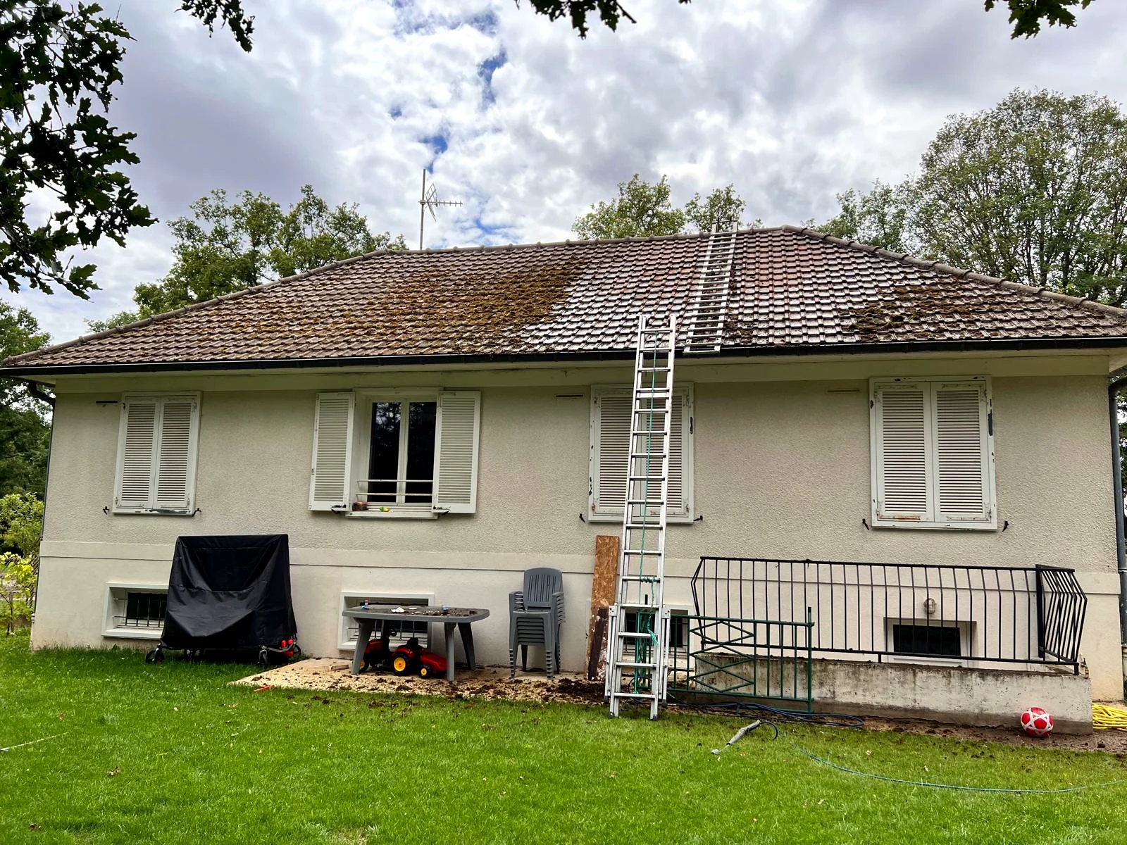 Toiture de plain-pied envahie par la mousse et les lichens, tuiles qui retiennent l'humidité.